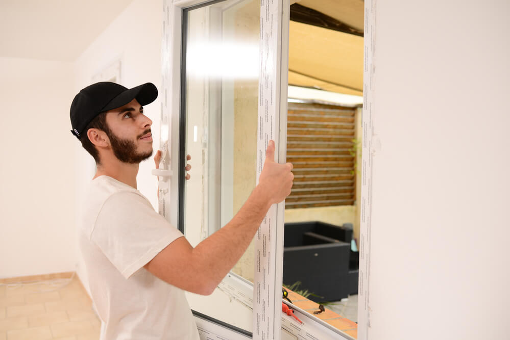 handsome young professional man installing and replacing a new home windows in client house for improvement energy saving efficiency isolation