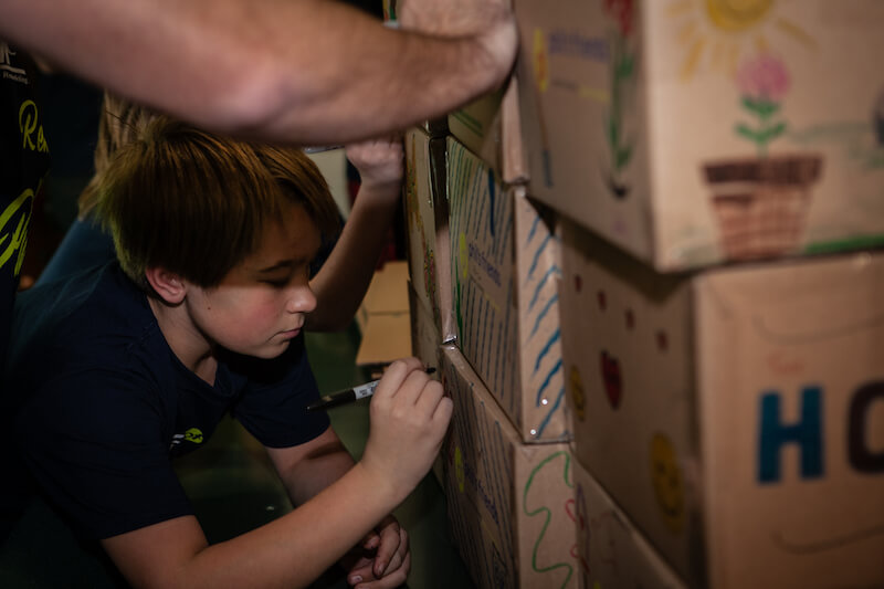 Children writing on a cardboard box.